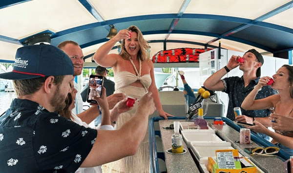 a girl raises her glass to cheer while others already drink their shots on the party boat
