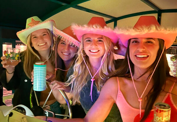 4 beautiful girls in bright festival pink hats posing in front of our boats raddar