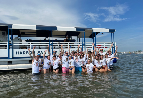 group of people posing in the water in front of our party boat