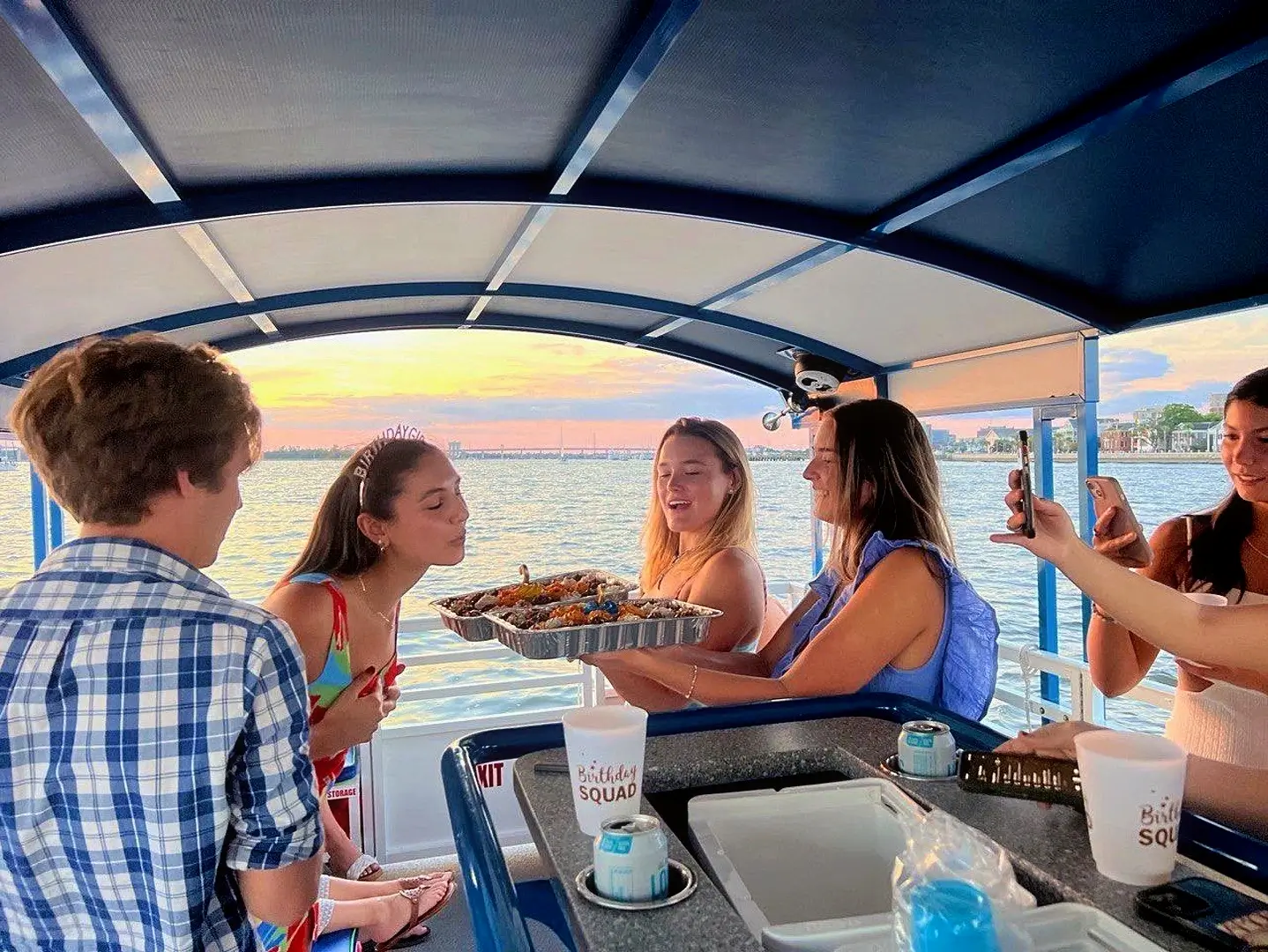 Group celebrating a birthday with drinks and music on a Charleston boat